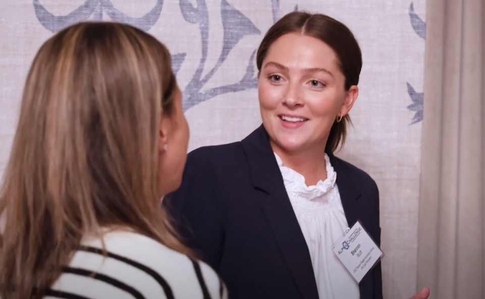 Woman smiling speaking to another woman at event